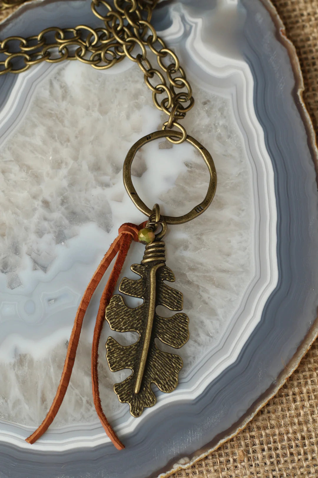 Antiqued gold necklace with leaf charm and leather accent